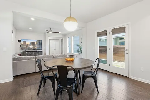 a large kitchen with white cabinets a sink dishwasher a dining table and chairs with wooden floor