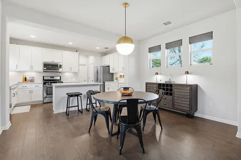 a dining room with a table chairs and a kitchen view