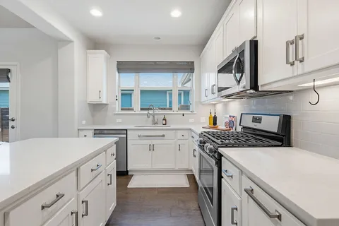 a kitchen with stainless steel appliances granite countertop a sink stove oven and white cabinets