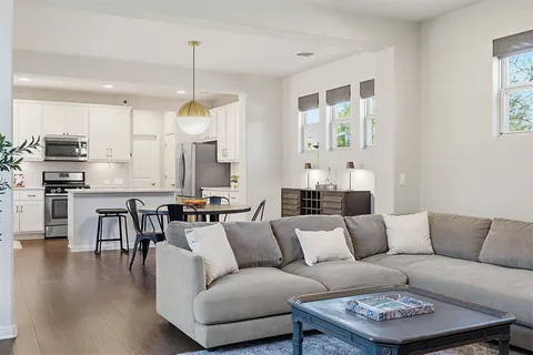 a living room with furniture kitchen view and a wooden floor