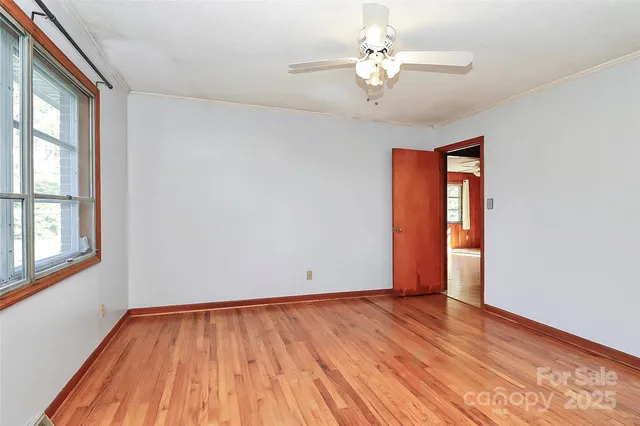 a view of an empty room with window and wooden floor