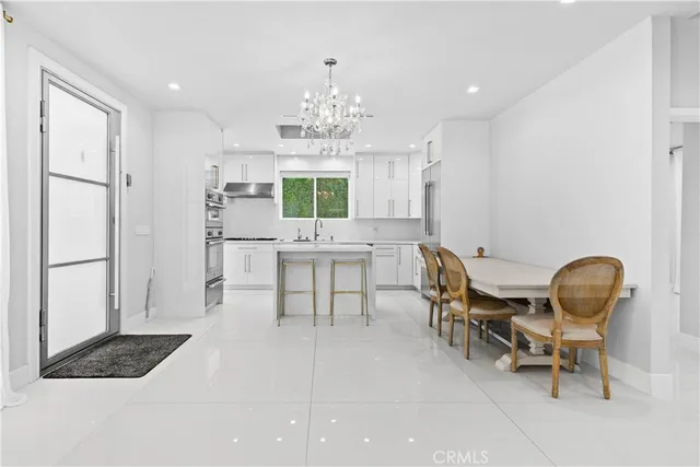 a kitchen with granite countertop a table chairs stove and white cabinets