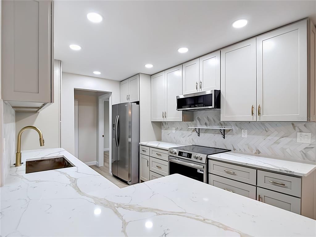 4536 Mitcher Road New Port Richey, FL 34652 - Photo 2 of 46 a kitchen with stainless steel appliances kitchen island granite countertop a refrigerator and a stove top oven