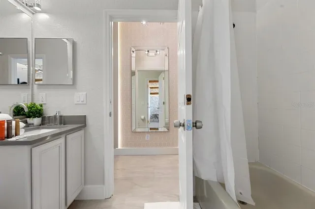 a bathroom with a granite countertop sink a mirror and shower