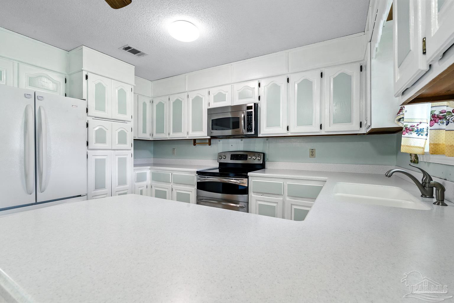 6160 Saddle Club Road Pace, FL 32571 - Photo 23 of 49 a kitchen with white cabinets and stainless steel appliances