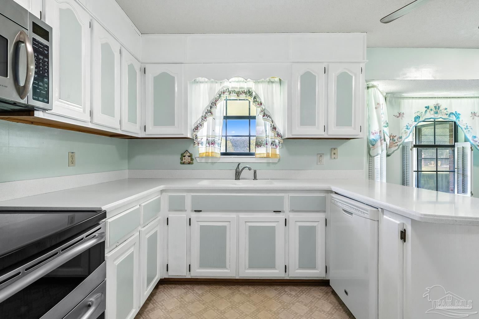 6160 Saddle Club Road Pace, FL 32571 - Photo 24 of 49 a kitchen with white cabinets appliances and a window