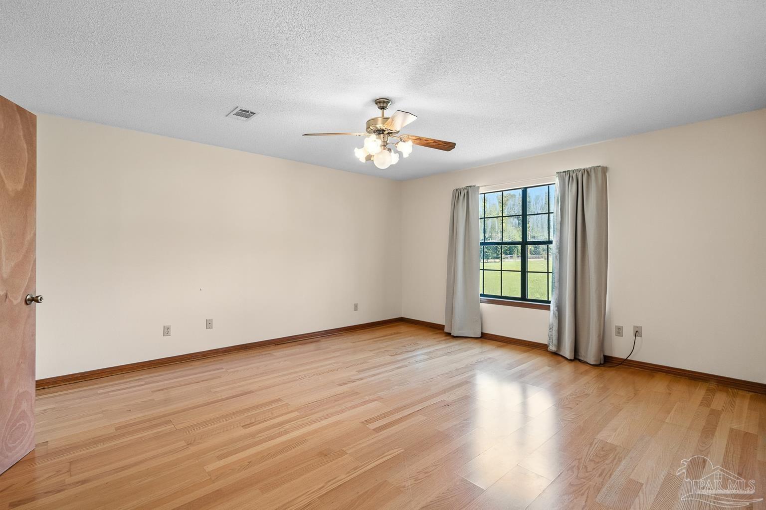 6160 Saddle Club Road Pace, FL 32571 - Photo 28 of 49 a view of an empty room with wooden floor and a ceiling fan