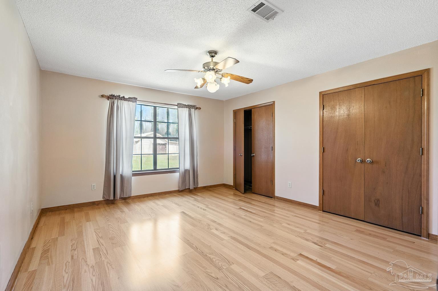 6160 Saddle Club Road Pace, FL 32571 - Photo 38 of 49 an empty room with wooden floor chandelier fan and windows