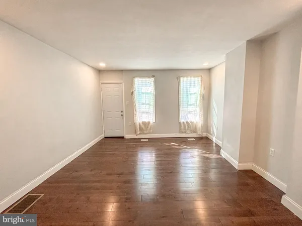 an empty room with wooden floor and windows with curtains view
