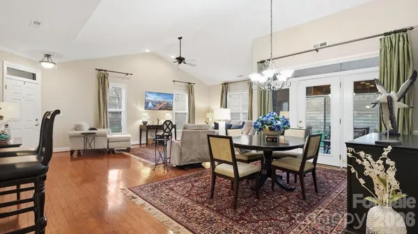a kitchen with stainless steel appliances a stove a sink a refrigerator white cabinets and couches with wooden floor