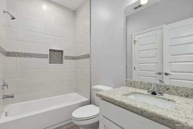 a bathroom with a granite countertop bathtub sink vanity mirror and toilet