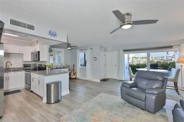 a living room with stainless steel appliances kitchen island furniture and a large window