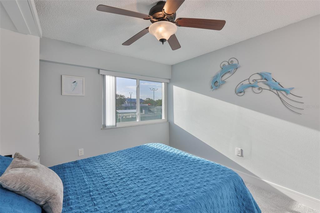 14800 Walsingham Road, Unit 1203 Largo, FL 33774 - Photo 21 of 68 a bedroom with a bed and a chandelier fan