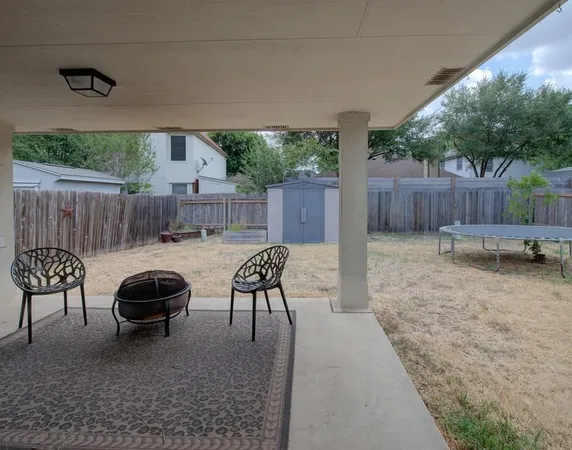 a view of a backyard with table and chairs potted plants and wooden fence
