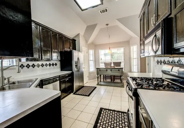 a kitchen with granite countertop a stove a sink and a refrigerator
