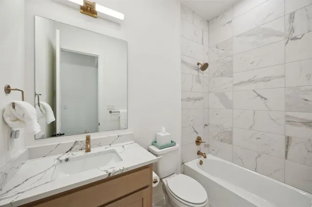 a bathroom with a granite countertop sink toilet tub and shower