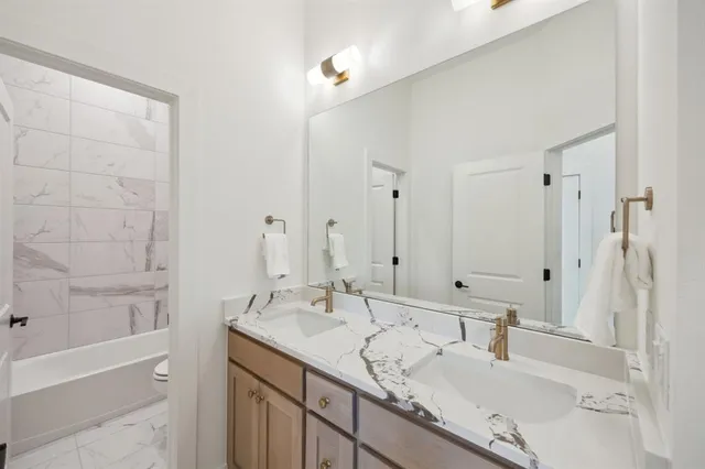 a bathroom with a granite countertop sink mirror and a bath tub