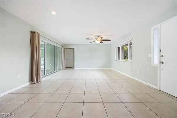 a view of an empty room with window and chandelier fan