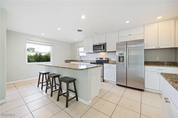 a kitchen with white cabinets a sink and a stove top oven with wooden floor