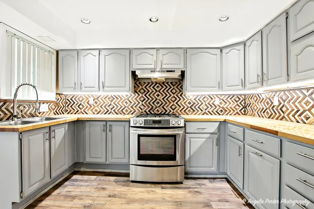 a kitchen with stainless steel appliances granite countertop a refrigerator oven a sink dishwasher and white cabinets next to a window