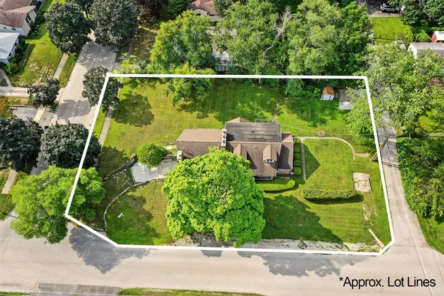 an aerial view of a house with swimming pool and large trees
