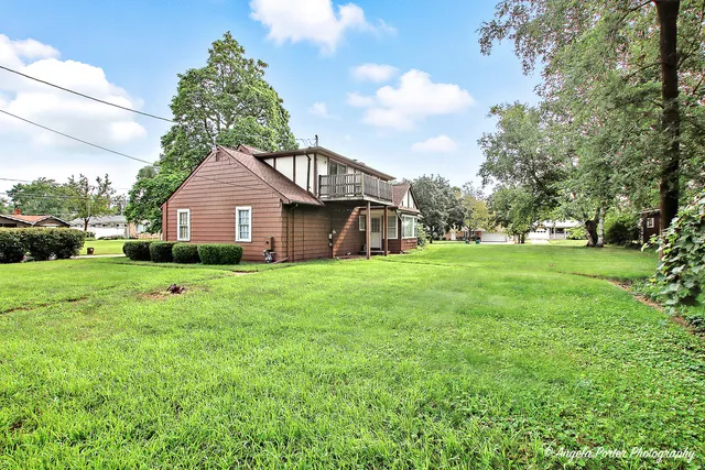 a view of a house next to a big yard and large trees