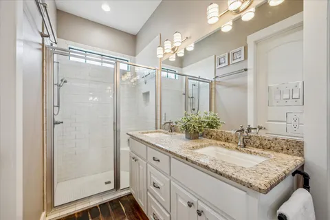 a bathroom with a granite countertop sink mirror and a shower
