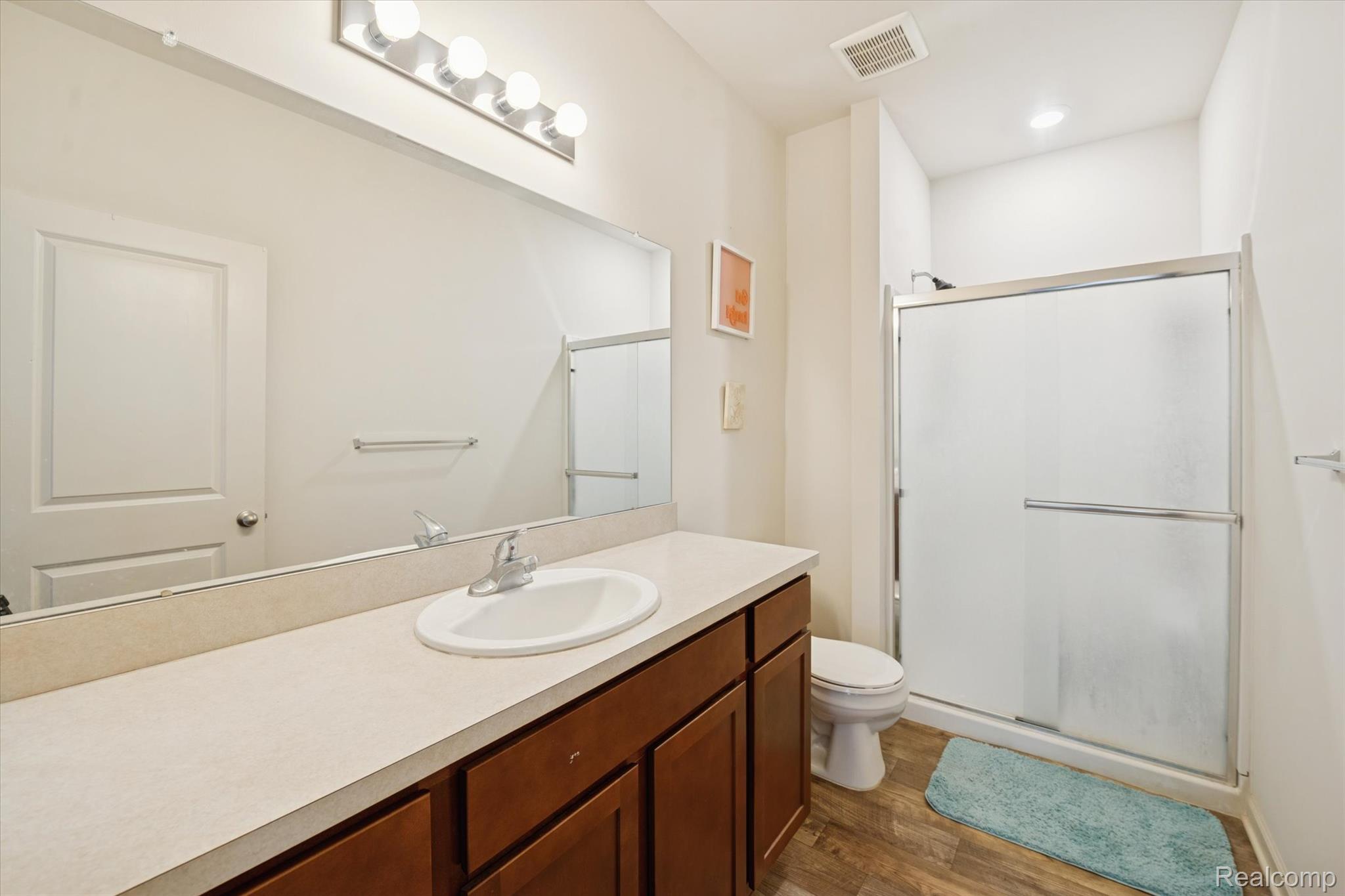10028 Ridge Run Street, Unit 10 Howell, MI 48855 - Photo 13 of 21 primary ensuite bathroom with large vanity, a stall shower, and dark wood-style floors