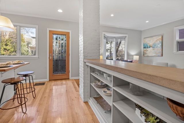 a large kitchen with stainless steel appliances a large window and wooden floor