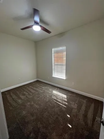 an empty room with a chandelier fan and windows
