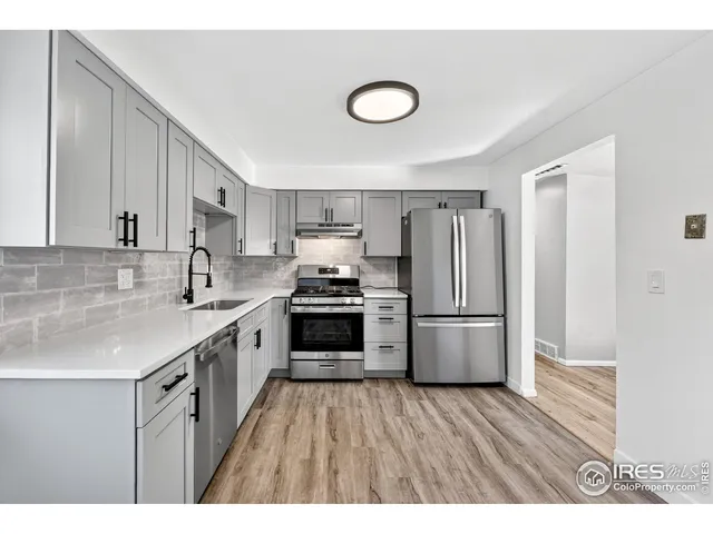 a kitchen with a sink dishwasher a refrigerator and a stove with wooden floor