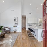 a living room with stainless steel appliances furniture wooden floor and a kitchen view