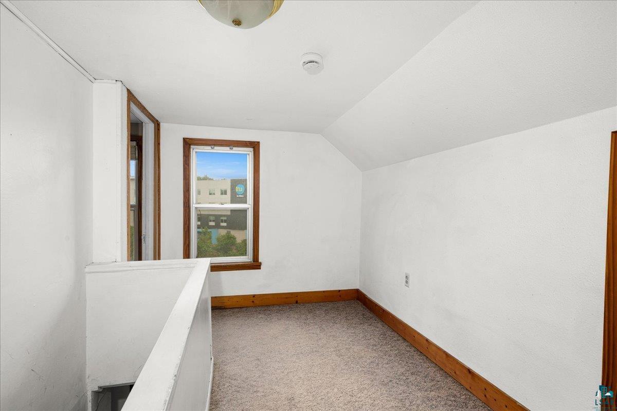 424 East Upham Road Duluth, MN 55811 - Photo 11 of 38 Sitting hallway room featuring a sloped ceiling, wood-trimmed window, wood-finish baseboards, and carpeted flooring