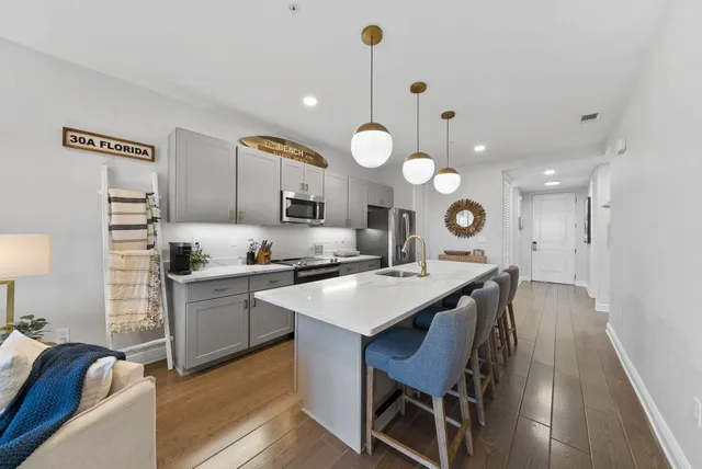 a kitchen with stainless steel appliances granite countertop a sink a stove top oven a chimney and a dining table