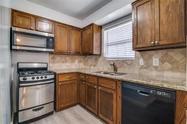 a kitchen with granite countertop cabinets stainless steel appliances and a sink