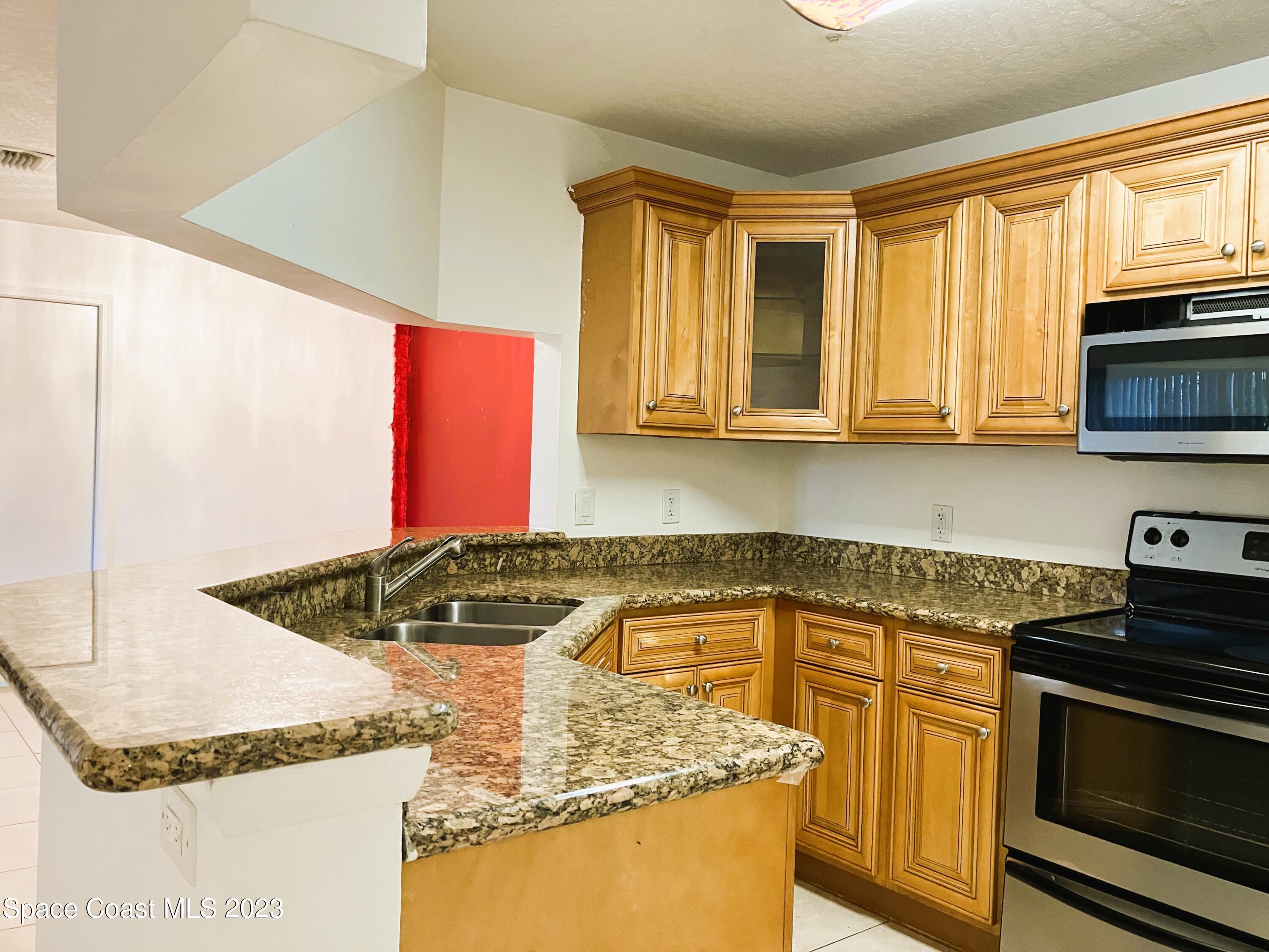 7667 North Wickham Road, Unit 304 Melbourne, FL 32940 - Photo 13 of 36 a kitchen with stainless steel appliances granite countertop a sink and a stove
