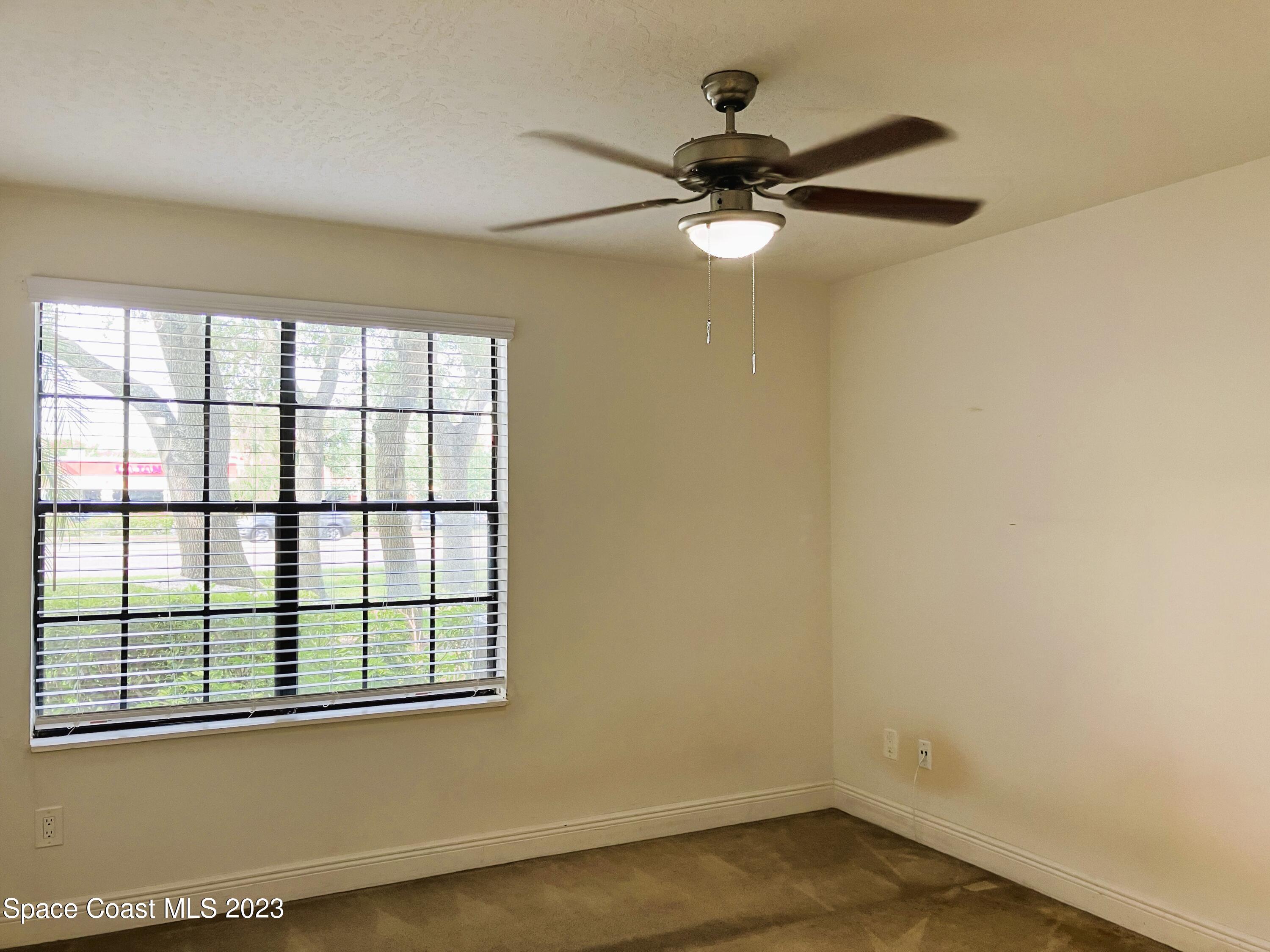 7667 North Wickham Road, Unit 304 Melbourne, FL 32940 - Photo 28 of 36 an empty room with wooden floor fan and windows