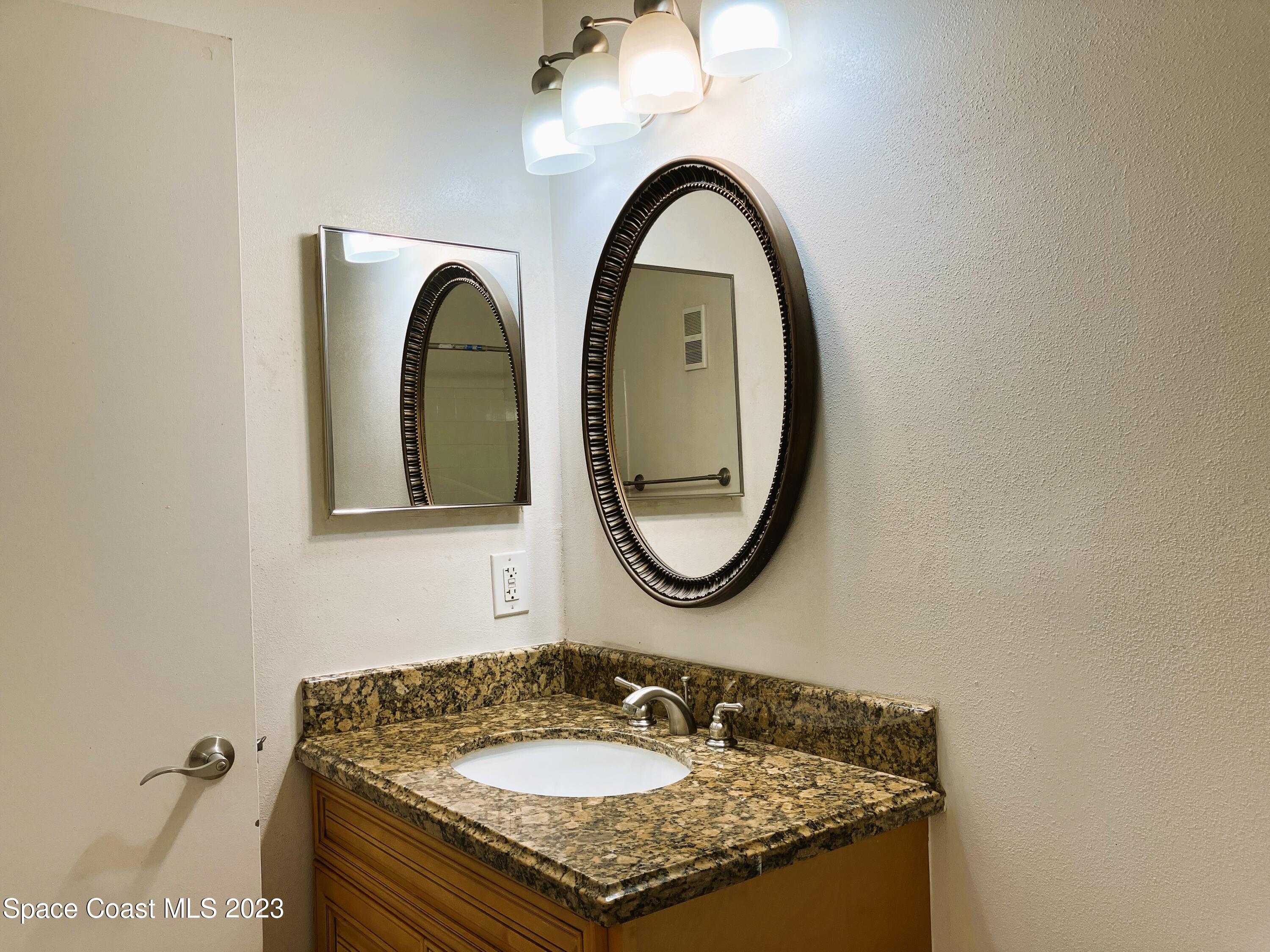 7667 North Wickham Road, Unit 304 Melbourne, FL 32940 - Photo 29 of 36 a bathroom with a granite countertop sink and a mirror