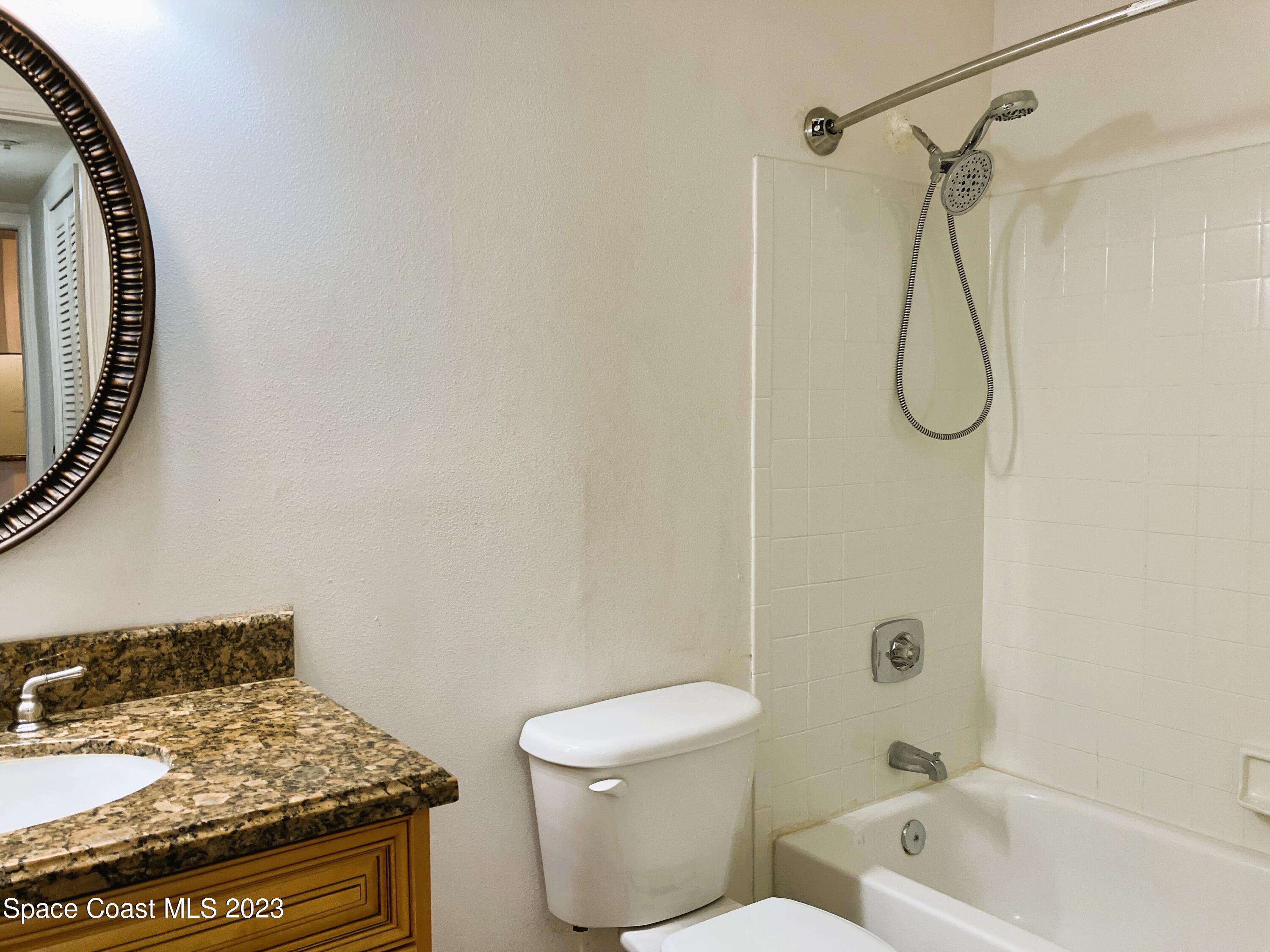 7667 North Wickham Road, Unit 304 Melbourne, FL 32940 - Photo 30 of 36 a bathroom with a granite countertop toilet sink and shower