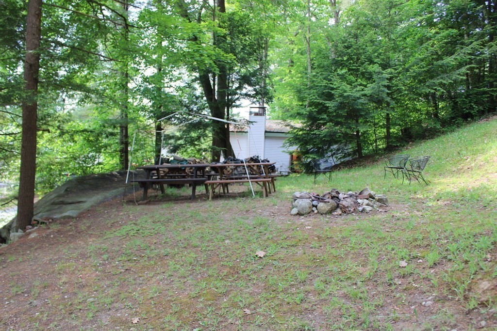 319 Wendell Road Warwick, MA 01378 - Photo 2 of 16 a backyard of a house with table and chairs in a forest