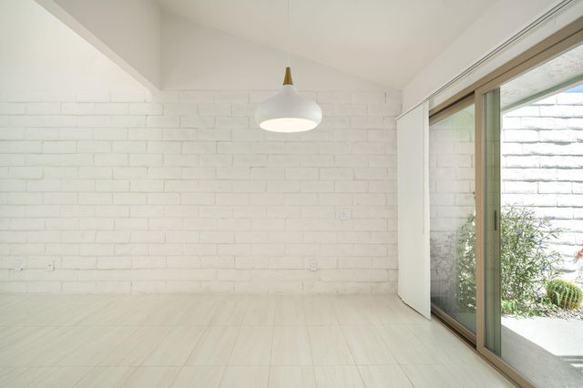 en empty room with kitchen view and wooden floor