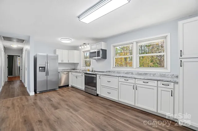 a kitchen with granite countertop white cabinets and white appliances