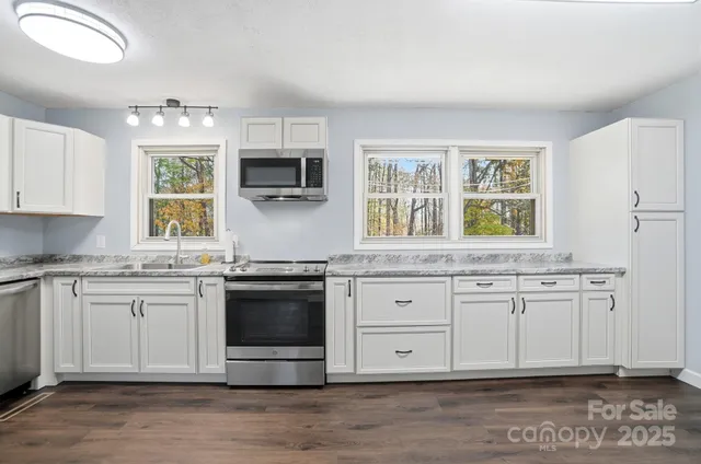 a kitchen with stainless steel appliances granite countertop a stove a sink and a microwave