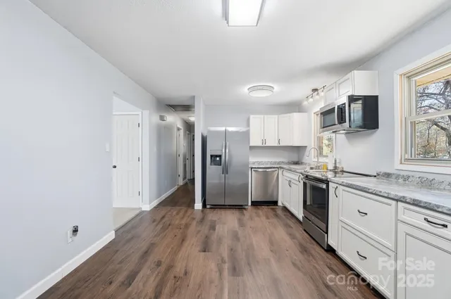 a kitchen with granite countertop a stove a sink and a refrigerator