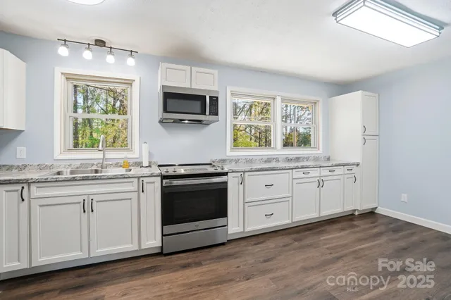 a kitchen with stainless steel appliances granite countertop a stove a sink and a microwave