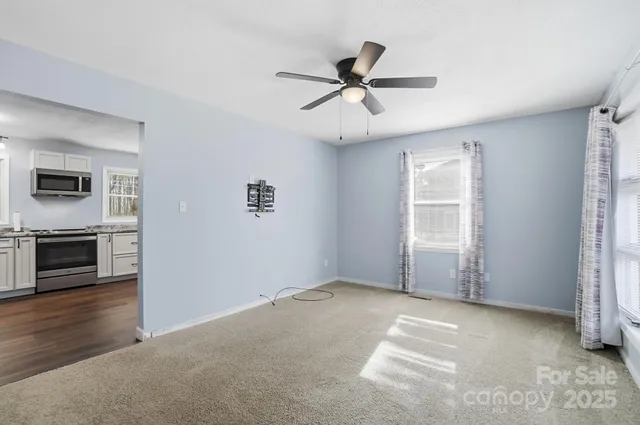 a view of a livingroom with a ceiling fan window and a kitchen