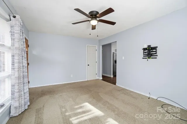a view of an empty room with a ceiling fan and window