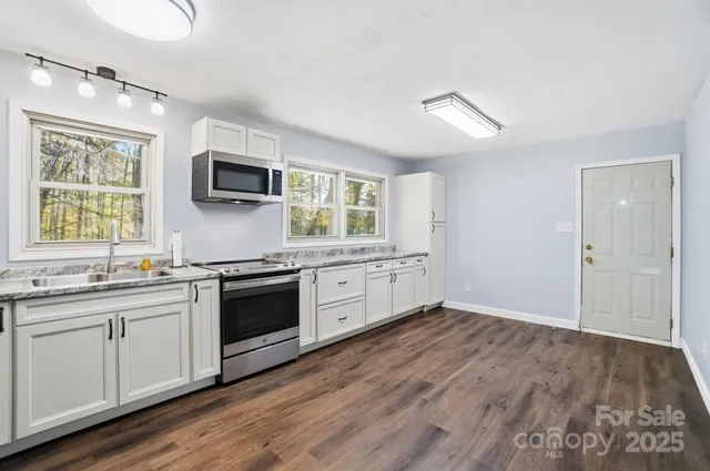 a kitchen with stainless steel appliances granite countertop a stove a sink and a microwave