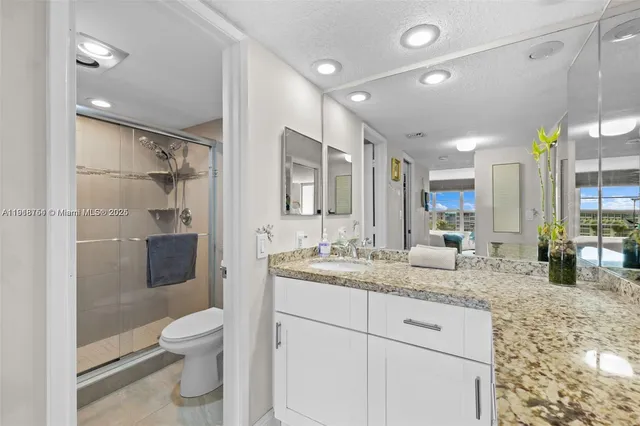 a bathroom with a granite countertop sink mirror and toilet