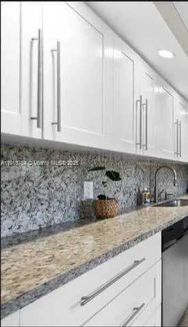 a kitchen with granite countertop white cabinets and sink